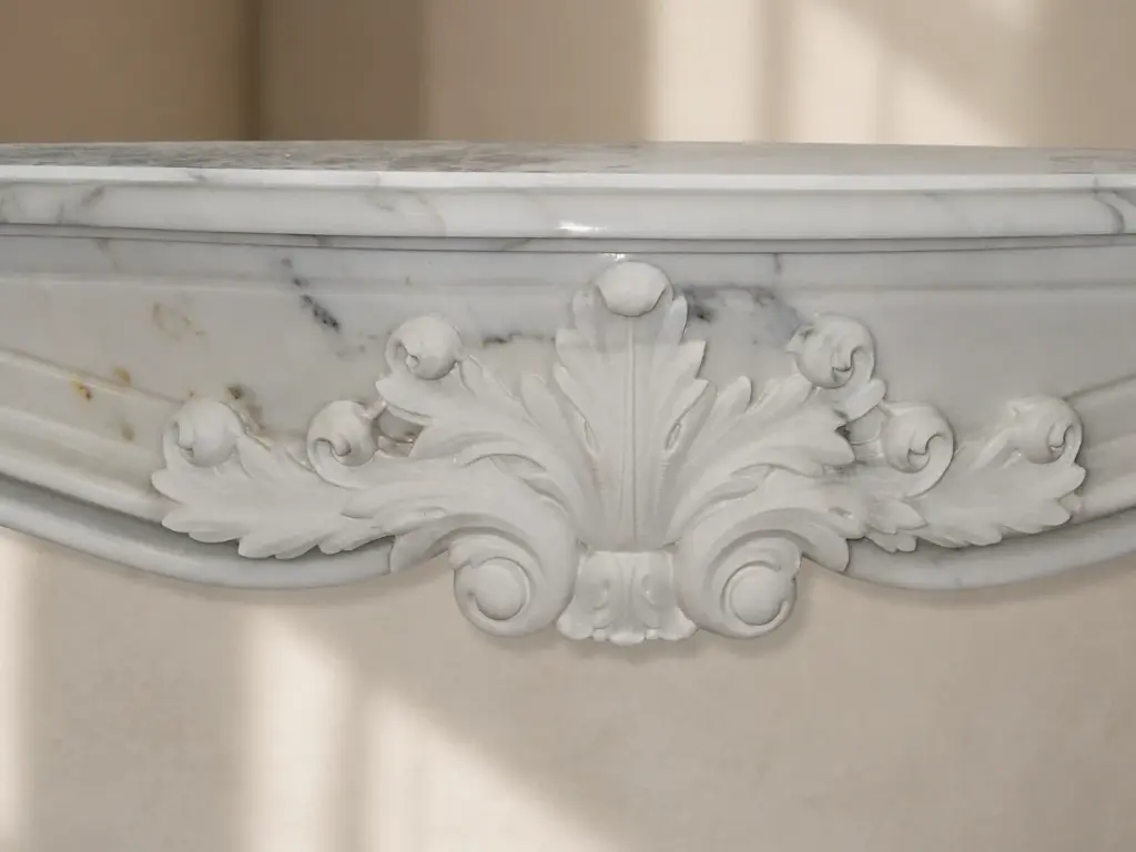 L'immagine mostra da vicino la fascia scolpita di un caminetto in marmo bianco