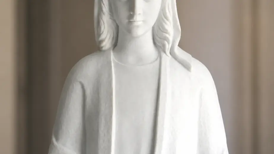 Particolare di madonna in marmo bianco, con figura frontale velata con braccia aperte e veste dalle linee essenziali