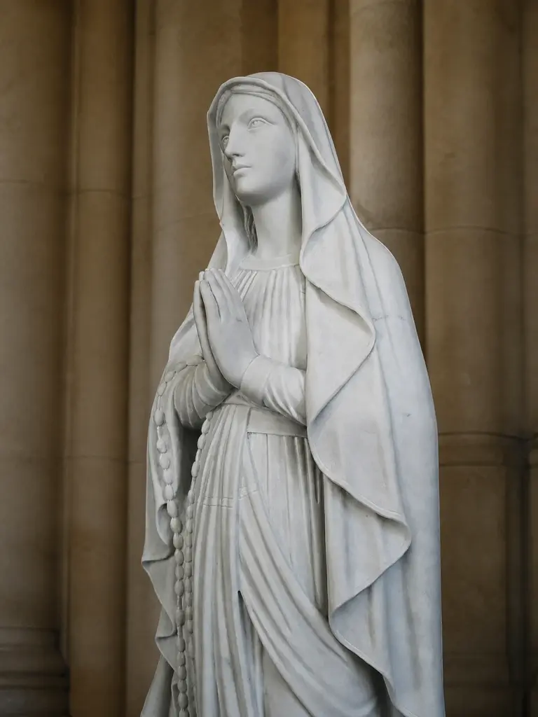 Madonna di lourdes in marmo bianco carrara, con figura intera con veste panneggiata e sguardo rivolto verso il basso