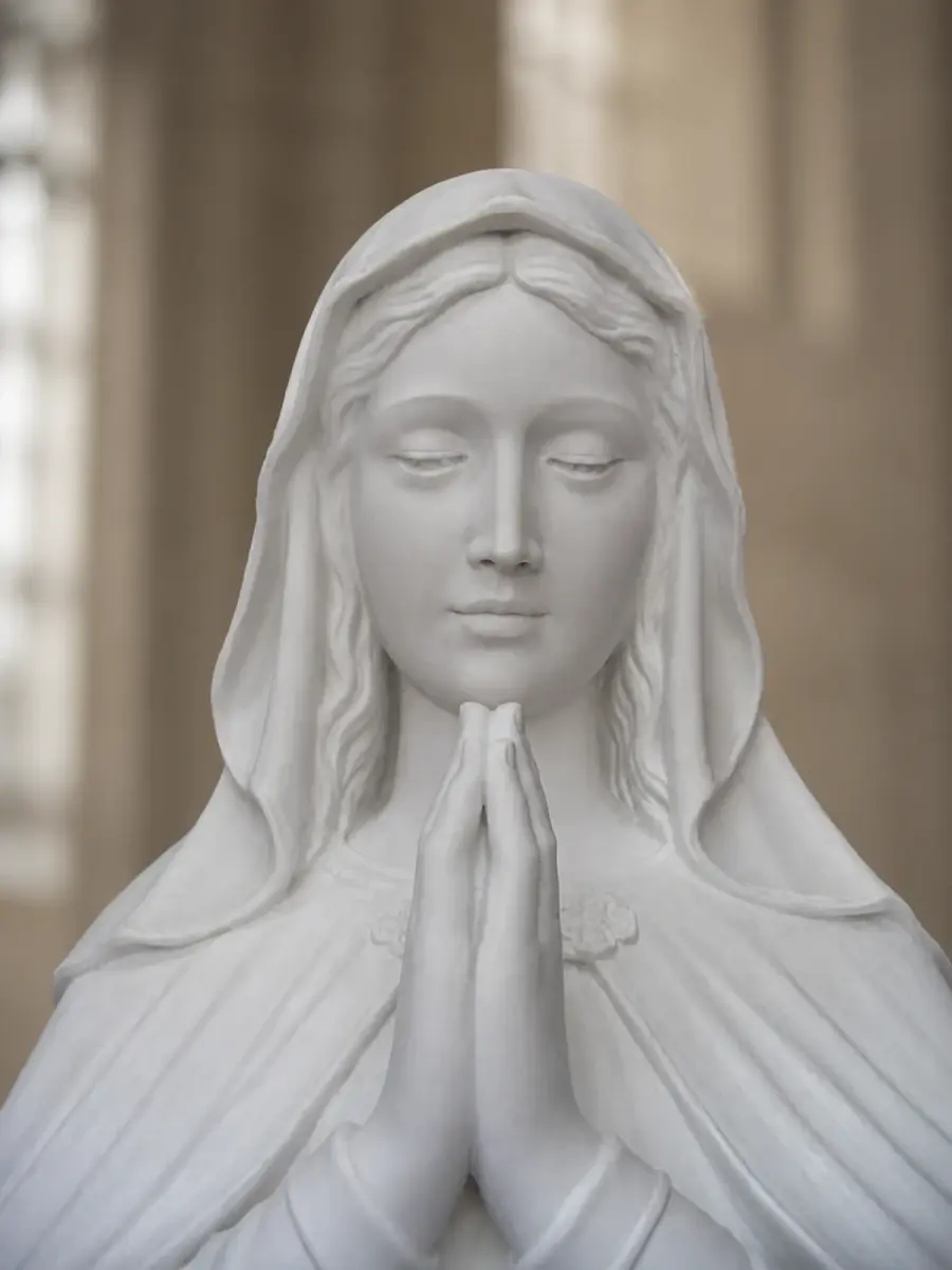 Madonna in preghiera in marmo bianco, con primo piano del volto velato e delle mani giunte